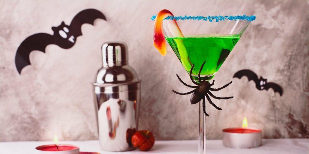 Bright green Witches Brew Cocktail in martini glass garnished with plastic spider