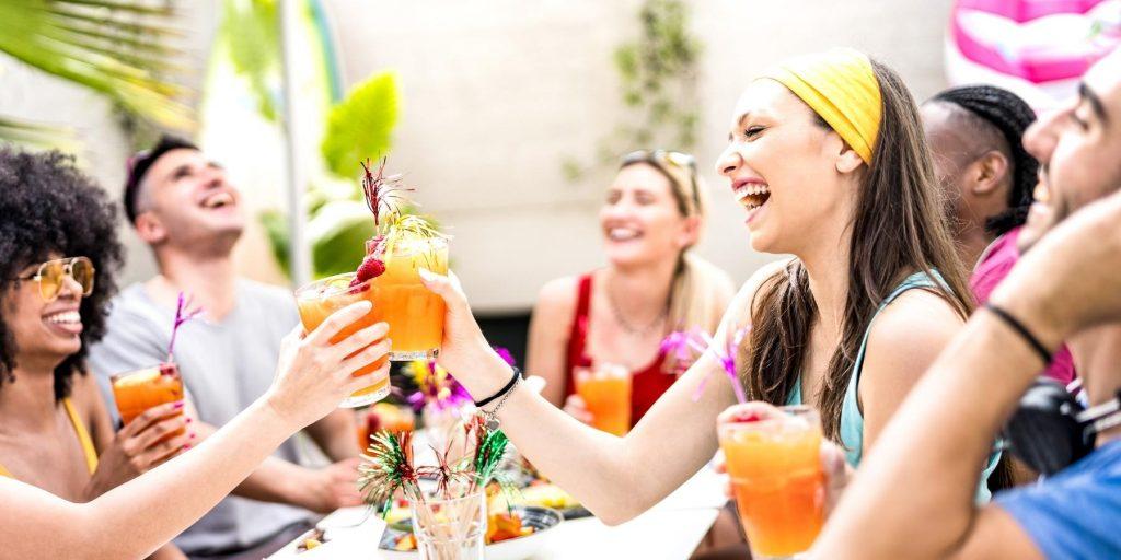 Group of friends clinking mocktail glasses and laughing