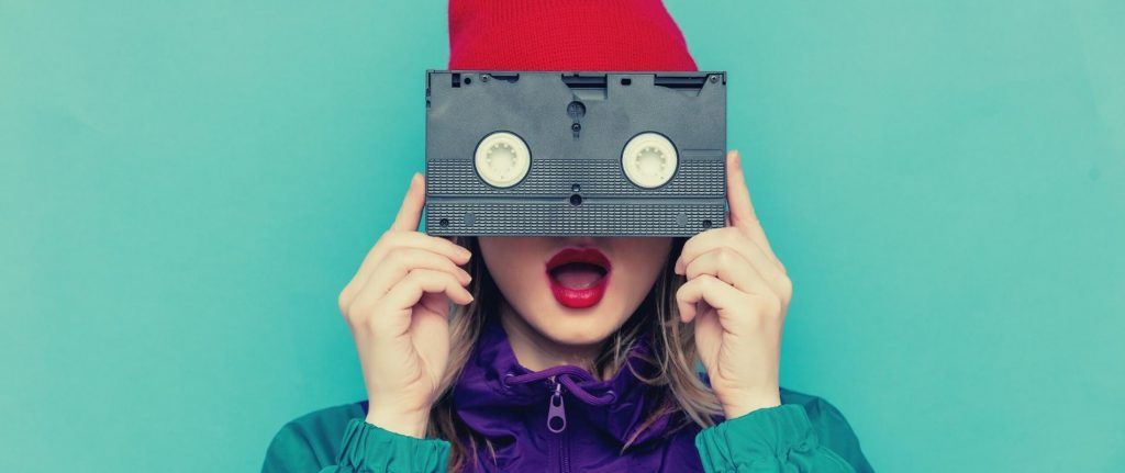 90s dressed woman hold a video cassette over her eyes