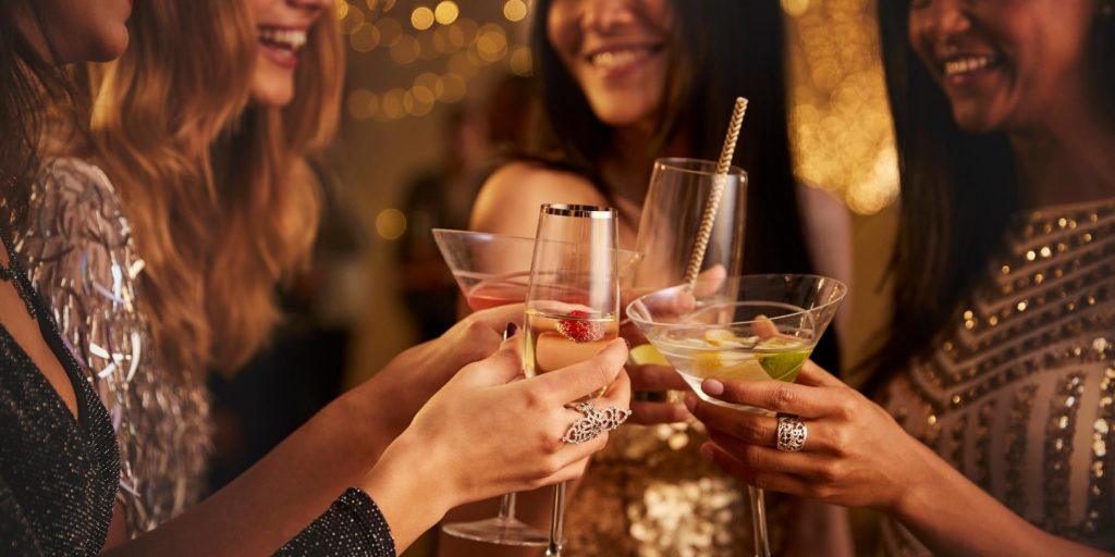 Front view of fashionably dressed woman clinking their cocktail glasses