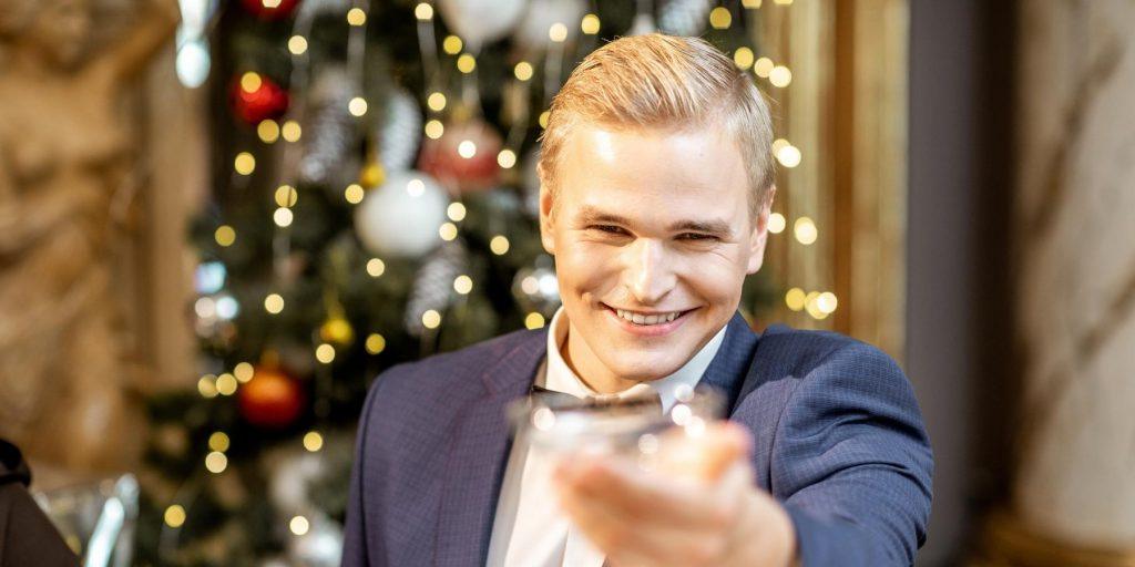 Gatsby-type blonde man looking at camera, toasting with champagne