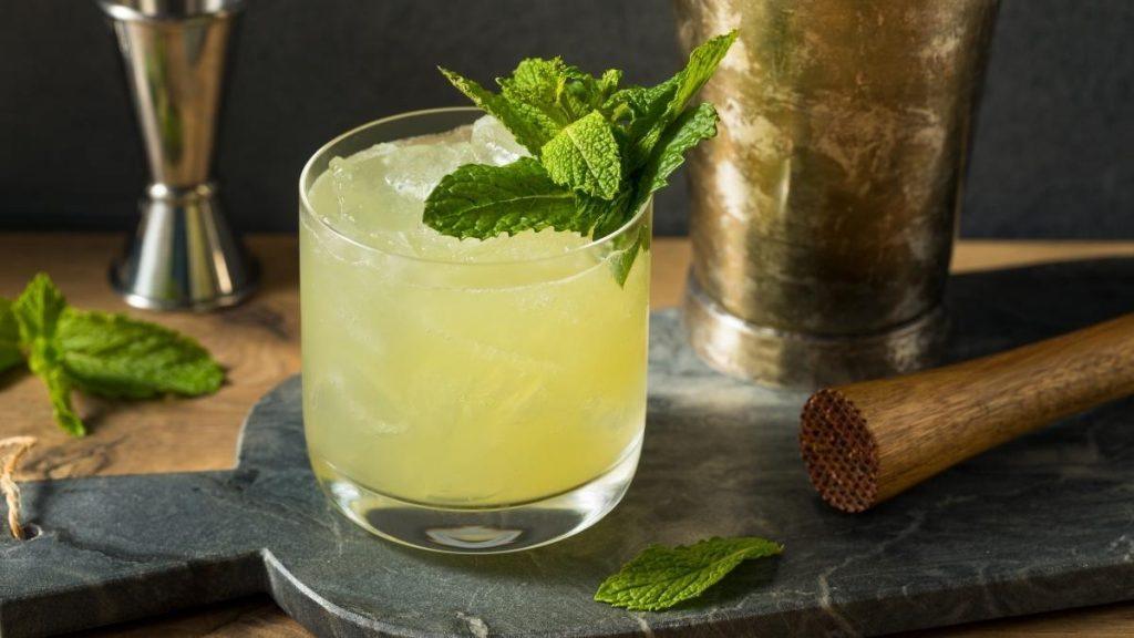 Green cocktail garnished with mint leaves on dark background