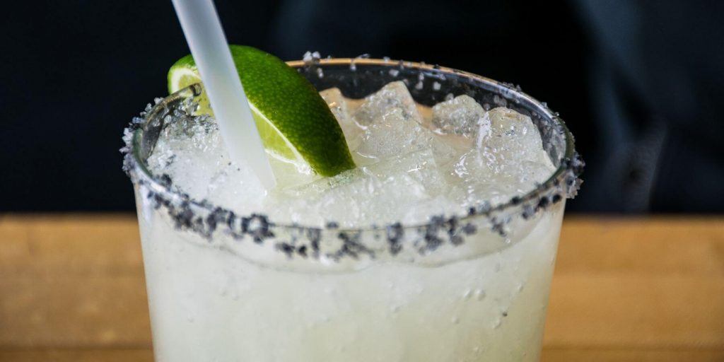 Close up shot of a black-salt-rimmed smokin Margarita with a lime wedge as garnish