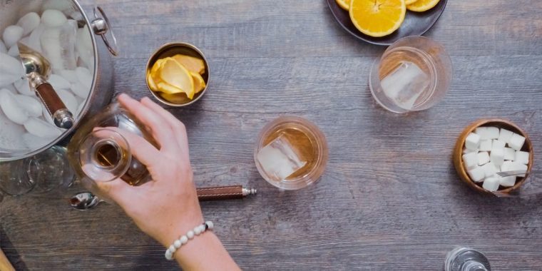 Top view of a woman's hands combining different cocktail ingredients to create easy 2 ingredient cocktails