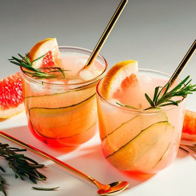 Two grapefruit and cucumber gin cocktails on a white background