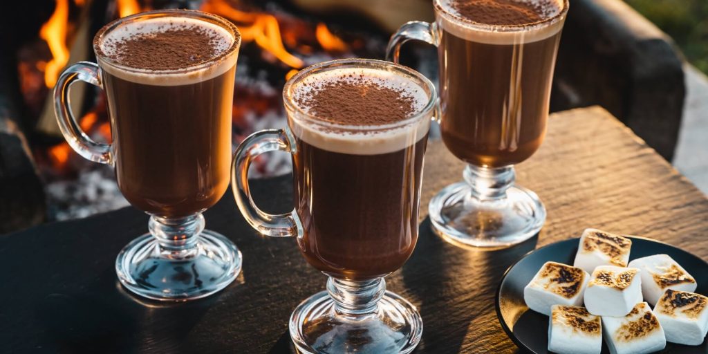 Three glass mugs of chocolate hot buttered rum with roasted marshmallows