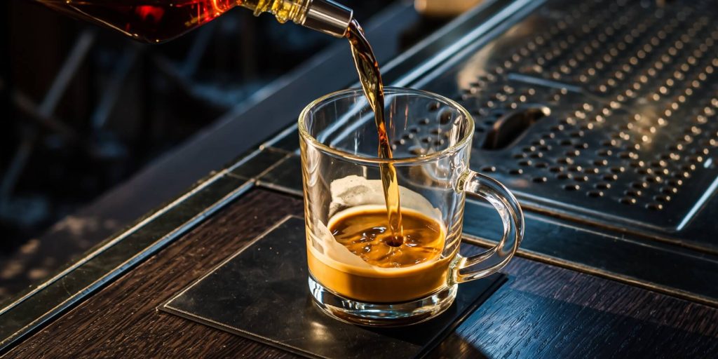 Pouring rum into a glass mug of coffee