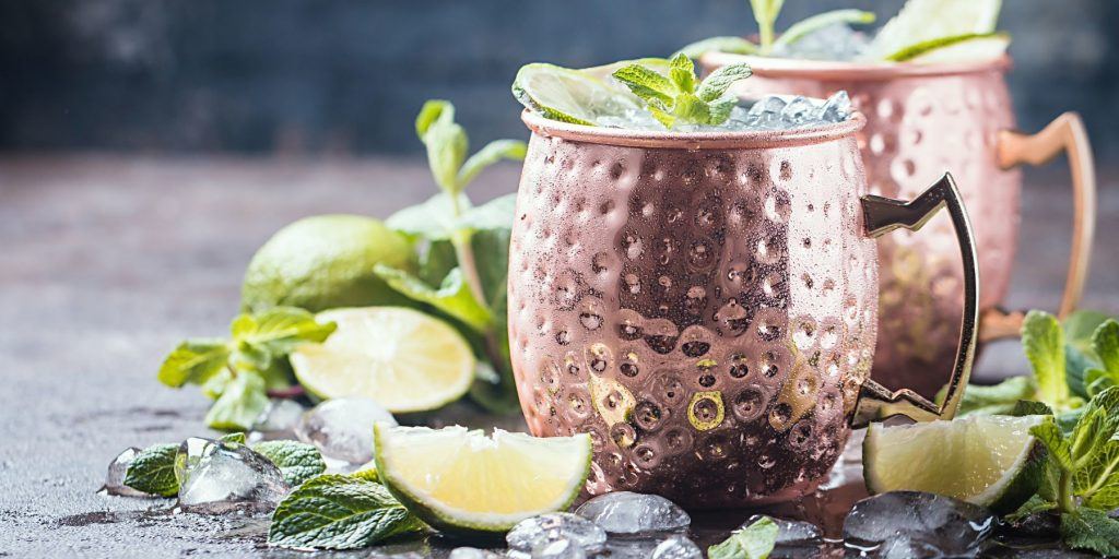 Moscow mule cocktail in copper cup with lime, ginger beer, vodka and mint garnish