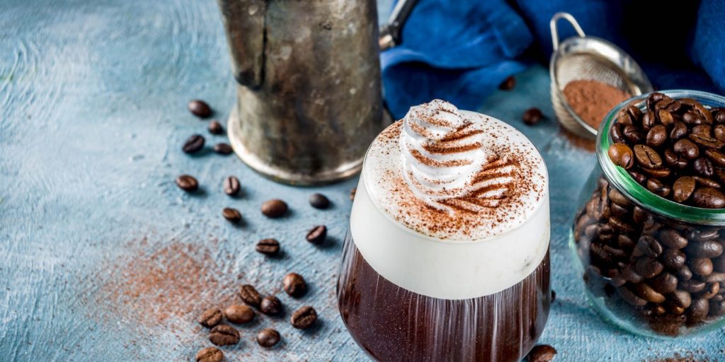 Two Irish Coffee glasses garnished with chocolate drizzle presented on a wooden table 