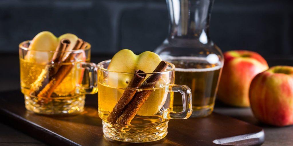 Front view of Hot Apple Cider Cocktail garnished with Cinnamon sticks and an apple slice
