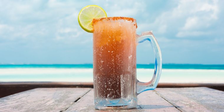 Beer glass of Mexican Michelada cocktail at the beach