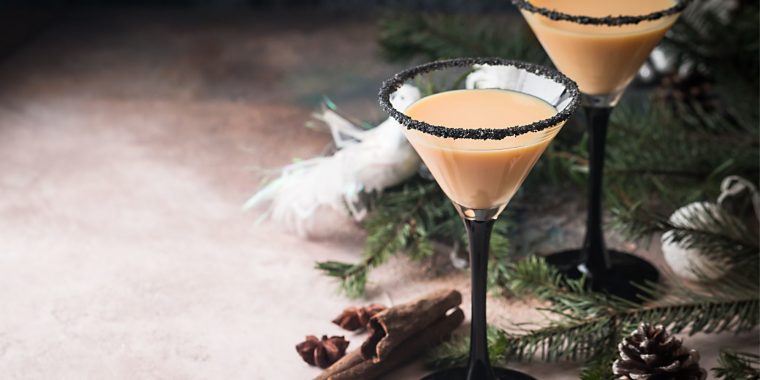 Traditional winter eggnog in martini glasses with milk, rum and cinnamon, christmas decorations