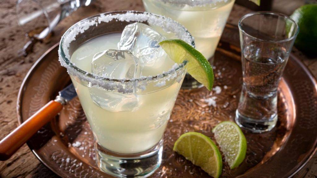 Top view of a pair of Cadillac Margaritas served on the rocks in salt rimmed glasses on a copper serving platter