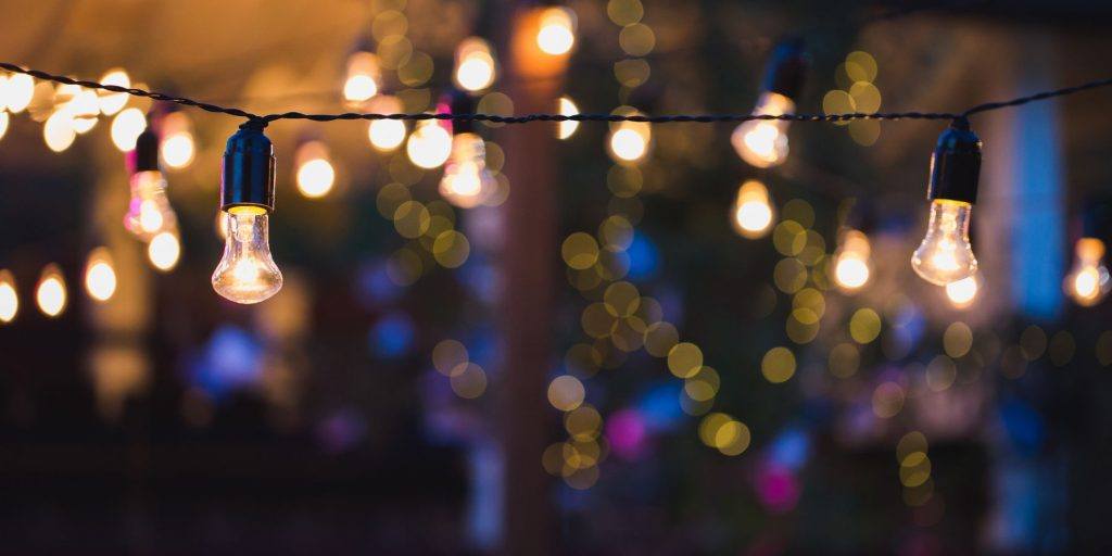 Close-up view of a string of naked bulbs in use as outdoor cocktail party decorations