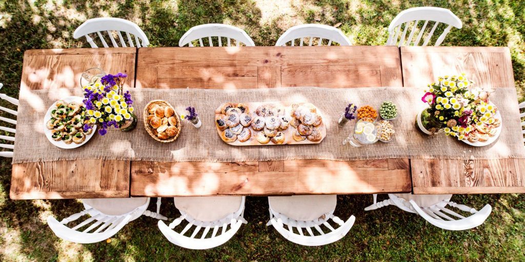 Top view of a lovely picnic spread on a wooden table as part of an outdoor cocktail party table setup