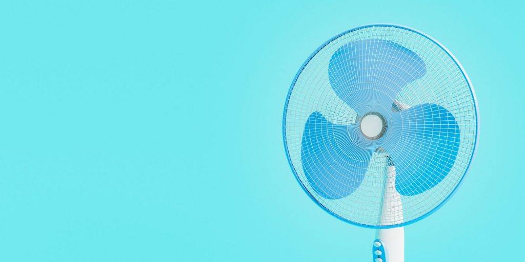 Close up of a blue fan against a light blue backdrop