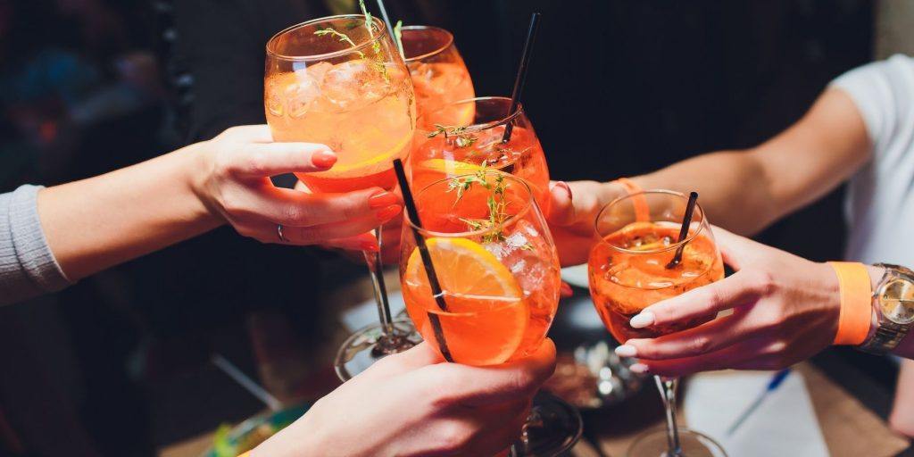 Close up of four friends clinking with glasses of Aperol Spritz with Champagne