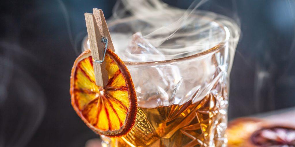 Old Fashioned smoking with dried orange garnish