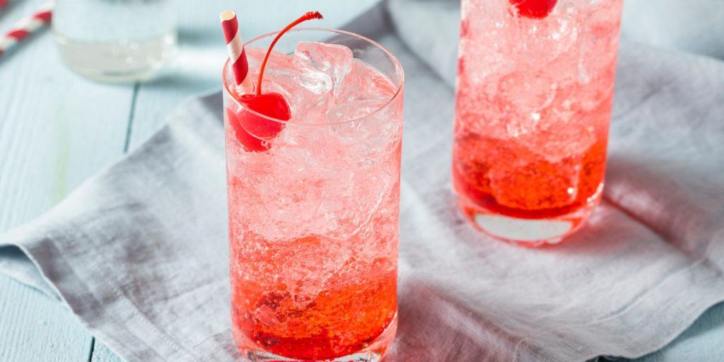 Close up top view of two Shirley Temple cocktails with cherries and paper straws