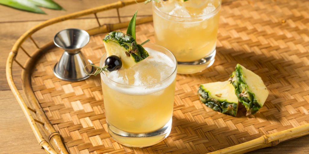Refreshing boozy Mai Tai cocktail on the rocks with cherry and pineapple garnish