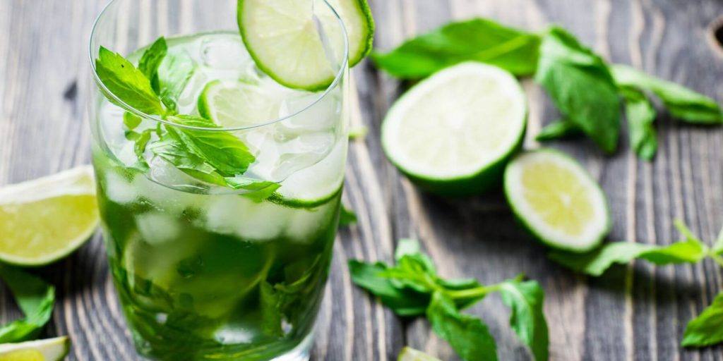 Mojito with mint & lime in a highball on a wooden board