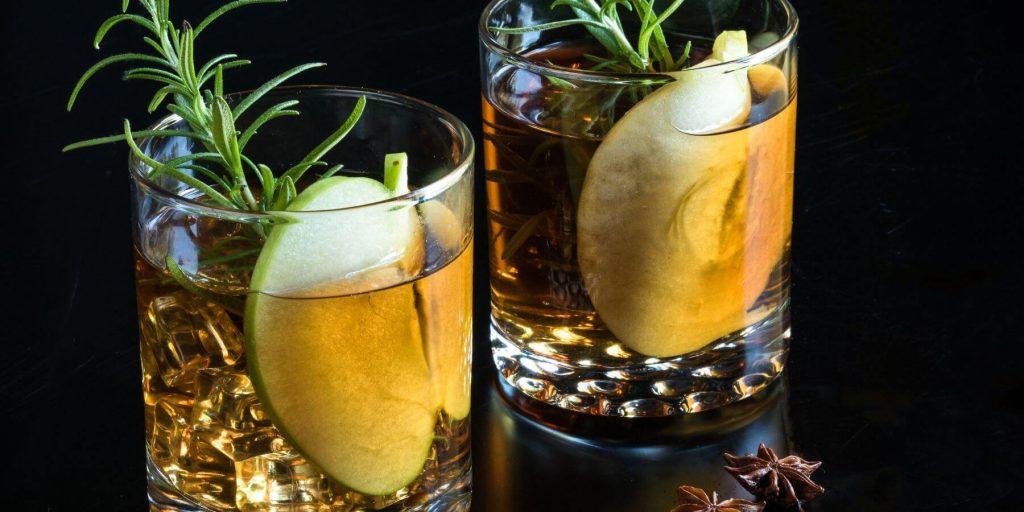 Two Apple Brandy Negronis garnished with green apple and rosemary