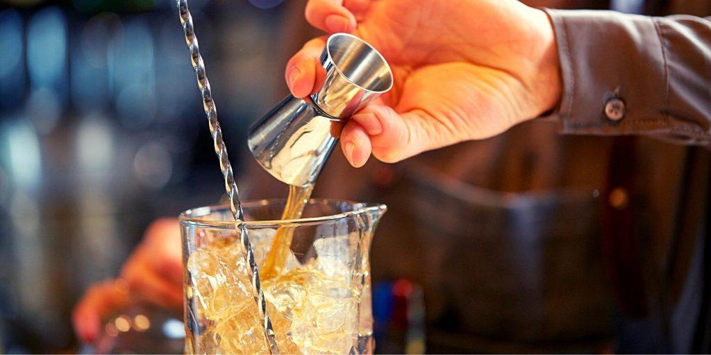 Double shot of liquor being poured into in a mixing glass