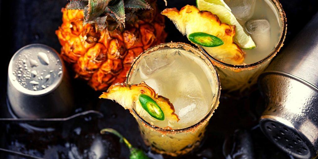 Top shot of Mezcalita cocktails with pineapple and jalapeno garnish 