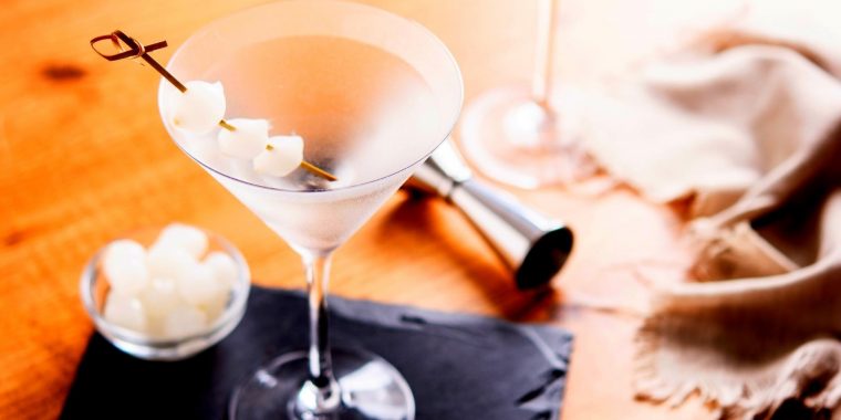 Top view of a pair of Gibson Martinis with skewered cocktail onion garnishes on a wooden surface