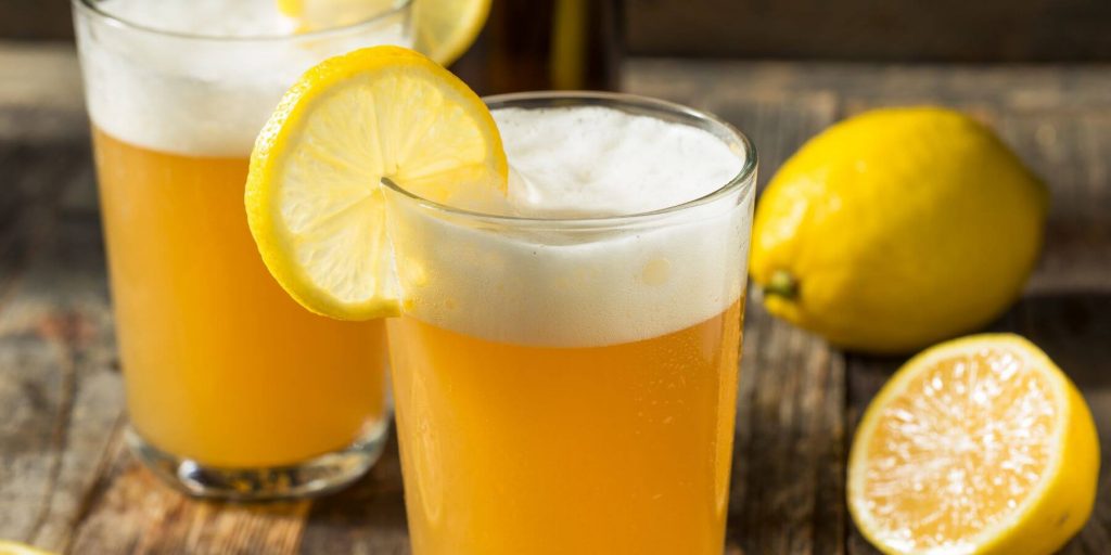 Beer shandies with lemon on wooden board