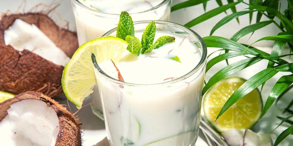 Indulgent Key Lime Martini with coconut and lime garnish and a palm frond in the background