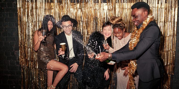 Friends opening a bottle of Champagne at New Year's Eve party