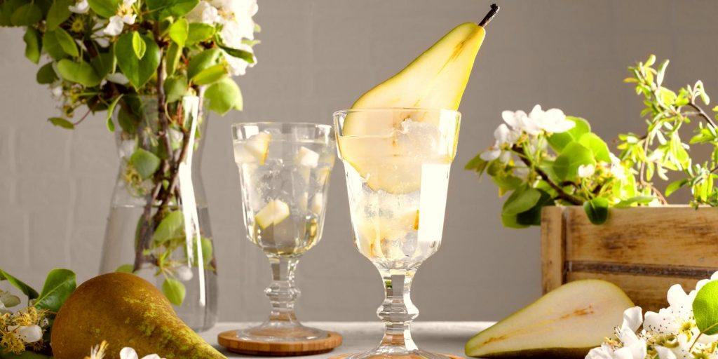 Pear Martinis with sliced pear garnish against a neutral backdrop with fresh pears in the foreground