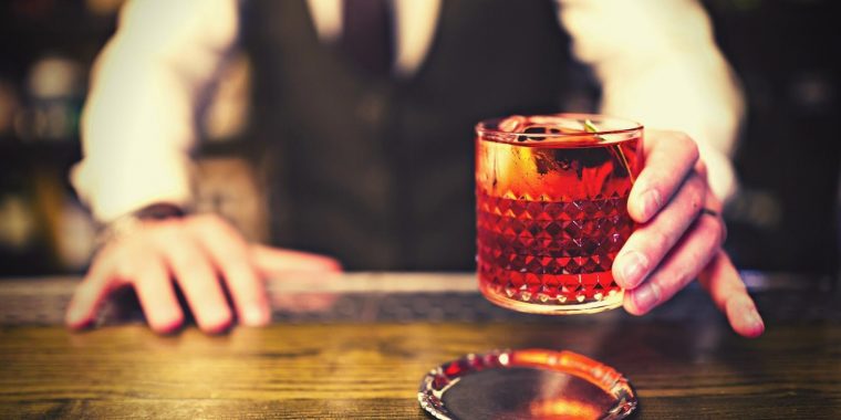Bartender serving a bright red Negroni cocktail