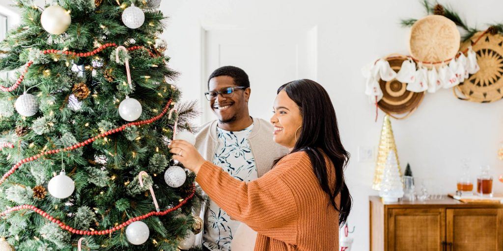 A coupld decorating a Christmas tree