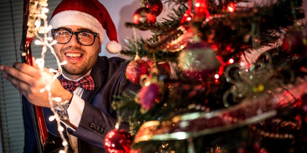 A man playing guitar in a Christmas hat