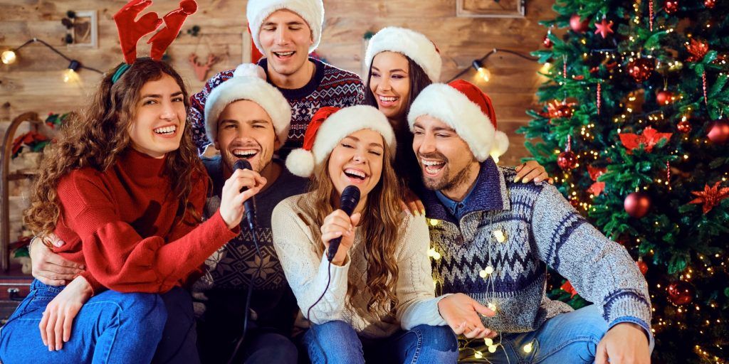 Five friends in Christmas hats singing karaoke