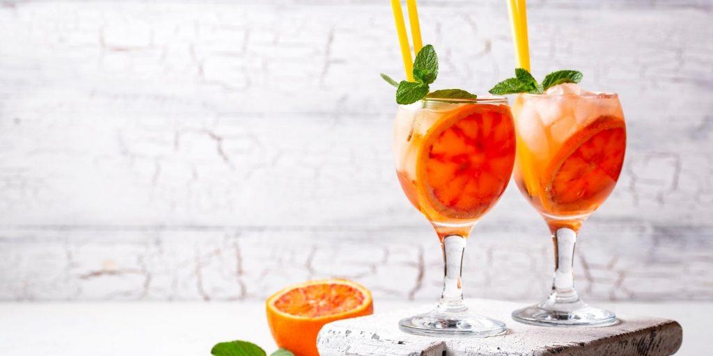 Two Orange Spritz cocktails, both a refreshing blend of Aperol, sparkling wine, and a twist of orange.