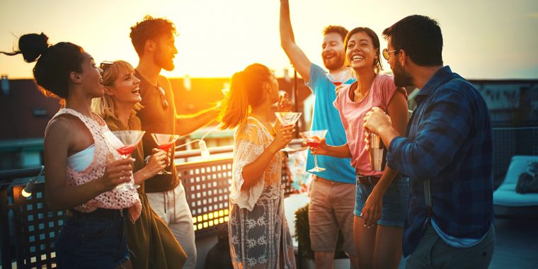 Friends enjoying popular cosmopolitan cocktails at a rooftop party