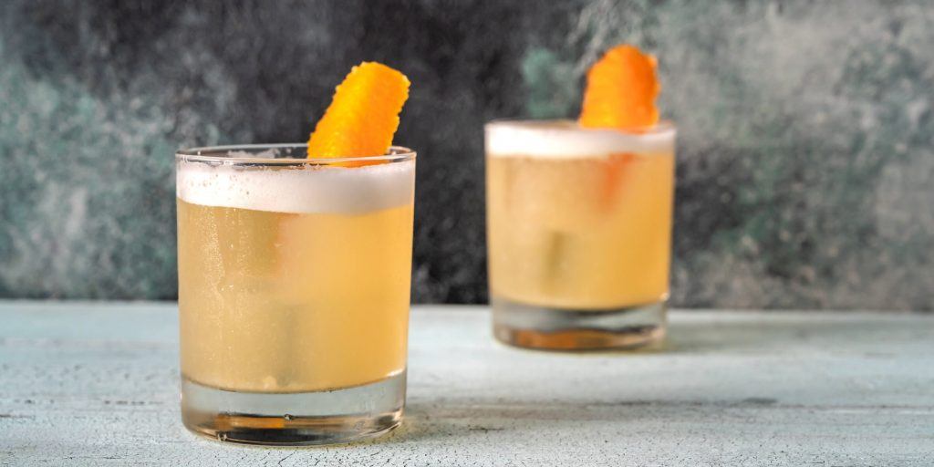 Two Bourbon Apple Sour cocktails with orange garnish