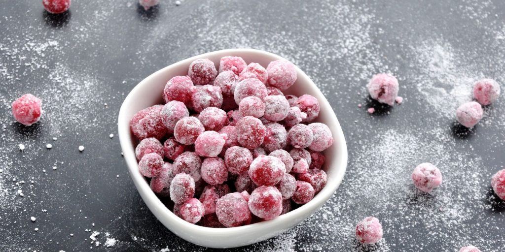Sugared cranberries for cocktails on a dusted dark background ready to be plopped into a pretty drink