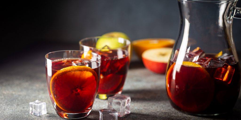 A jug of fruity rum punch with two glasses