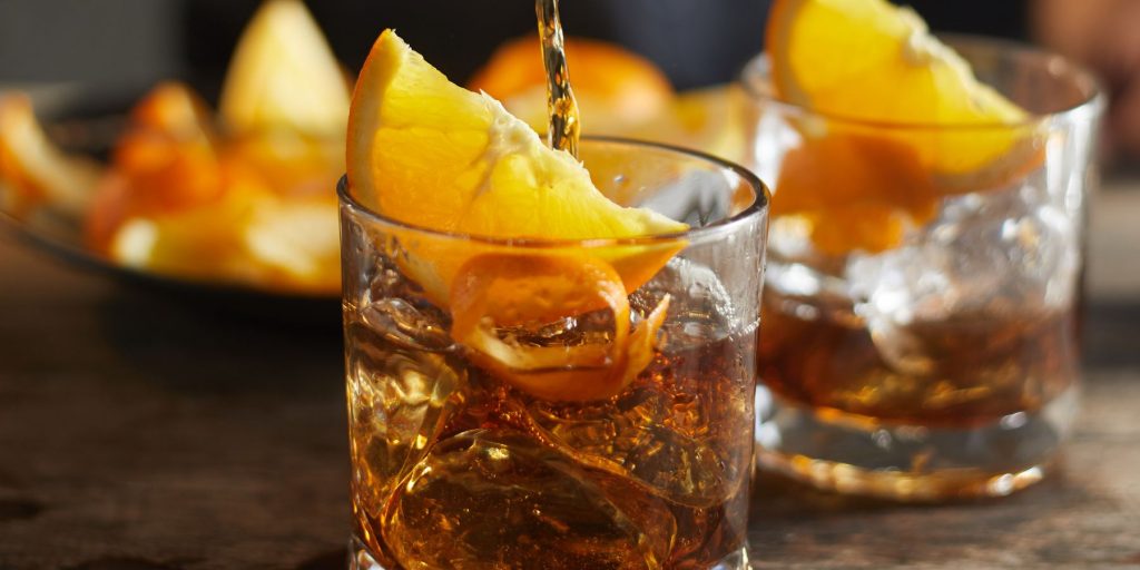Two Rum Old Fashioned cocktails garnished with orange slices