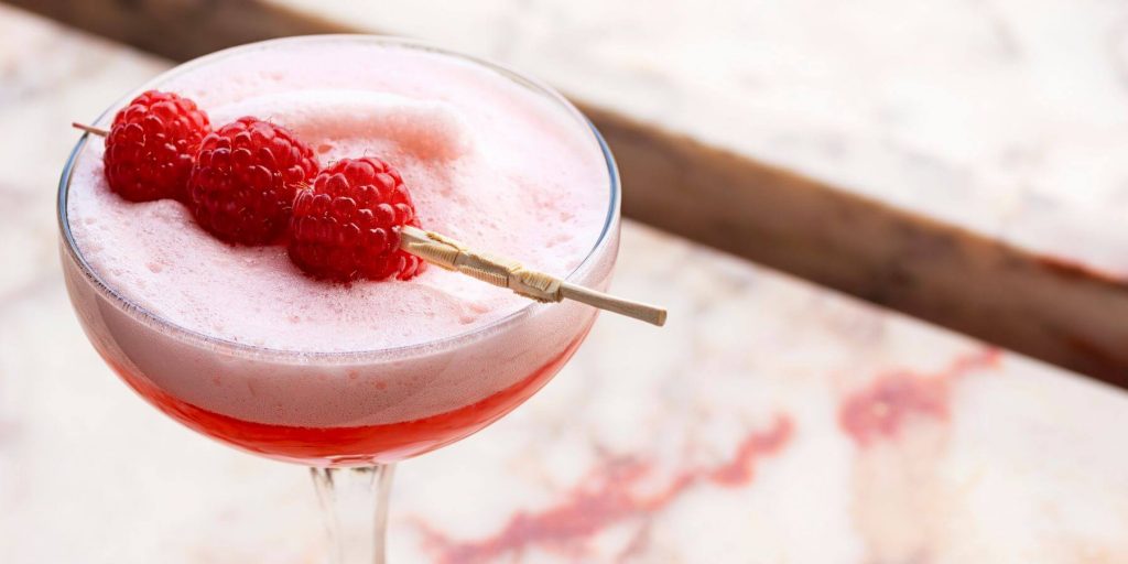 A vegan-friendly Clover Club cocktail garnished with ripe raspberries