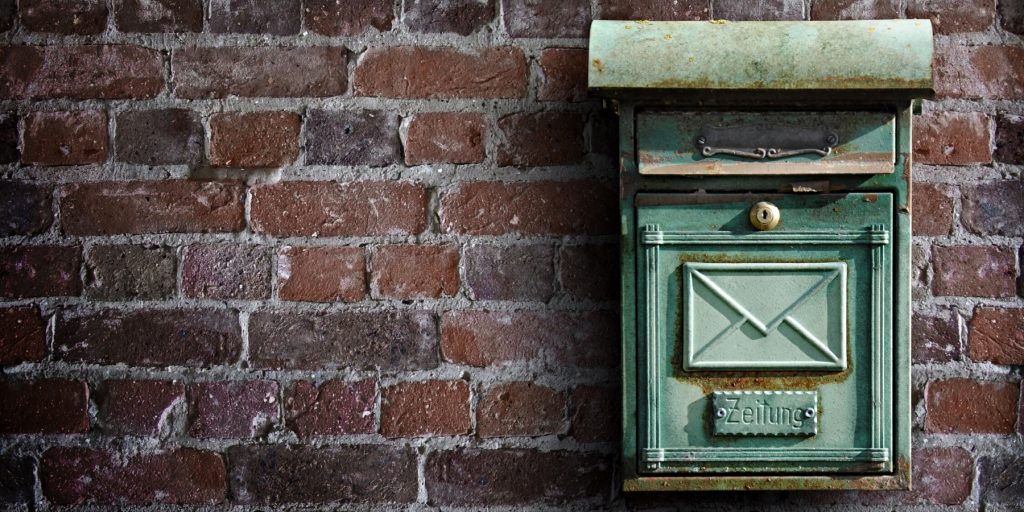 An old style post box on a brick wall