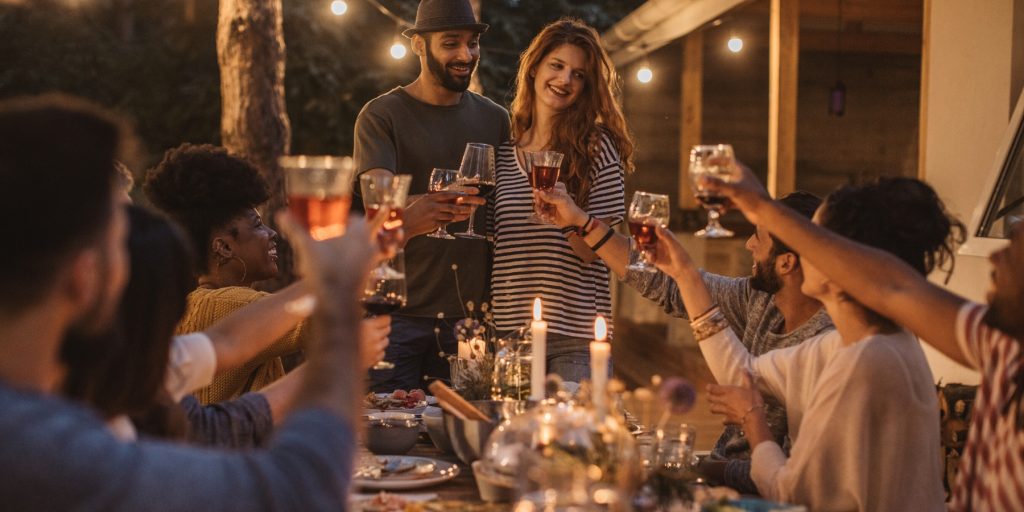 A couple toasting their friends at a dinner table