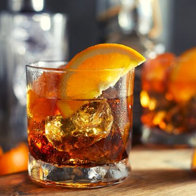 Two Irish Whiskey Old Fashioned cocktails with fresh orange garnish served on a wooden platter