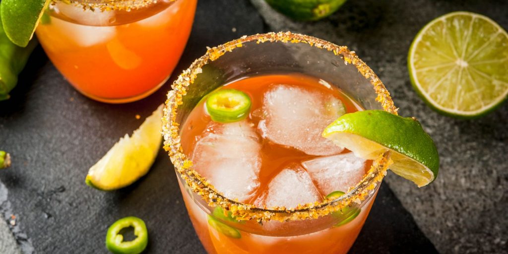 Top view of a Mezcal Michelada cocktail with a paprika rim and a lime wedge as garnish