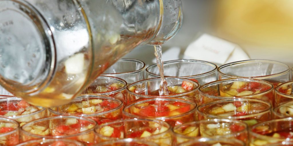 Side view of a batch cocktail being poured into pre-prepped glasses