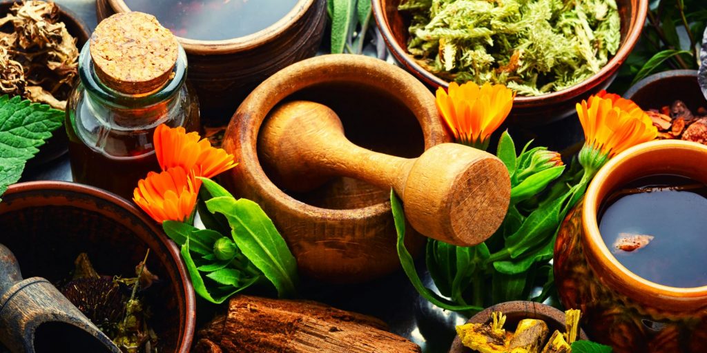 Close up of a top view of a table filled with medicinal herbs and tools used to make herbal elixirs and remedies 